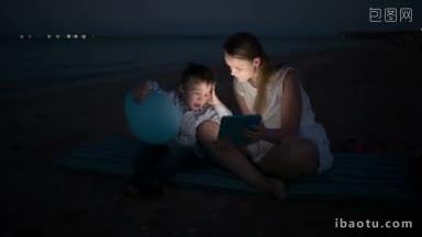晚上，母亲和她的小儿子在海滩上用<strong>触控</strong>板